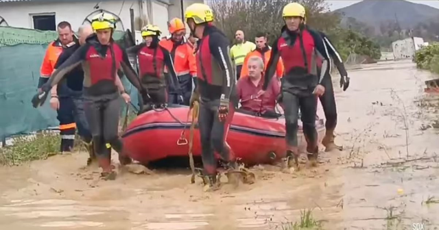 A woman and her dog swept away by floodwaters in Spain were rescued at the last moment