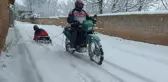Motosiklete bağladığı kızaklarla çocukları karda eğlendirdi
