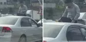 Seyir halindeki otomobilin üzerine oturup içki içti