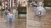 Sağanakta suyla dolan caddede içine girdiği büyük şeffaf balonla ilerledi