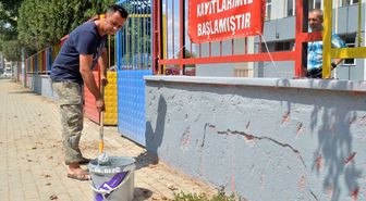 Okul müdürü elinde fırçayla okulu boyuyor