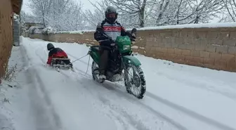 Motosiklete bağladığı kızaklarla çocukları karda eğlendirdi