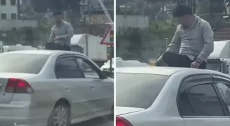 Seyir halindeki otomobilin üzerine oturup içki içti