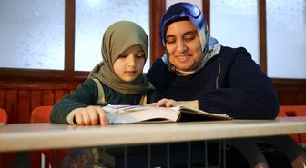 Çevresini silüet olarak gören kadın, yediden yetmişe Kur'an-ı Kerim öğretiyor
