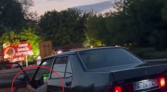 Otomobilinin sol ön kapısını açıp, ayağıyla tutarak trafikte ilerledi
