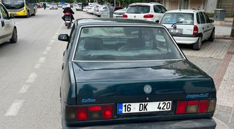 Otomobilinin sol ön kapısını açıp, ayağıyla tutarak trafikte ilerledi