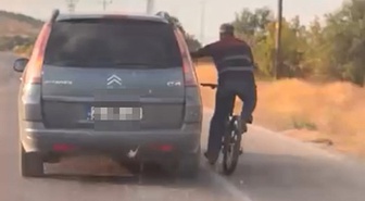 Elazığ'da bisiklet sürücüsü aracın kapısına tutunarak tehlikeli şekilde ilerledi