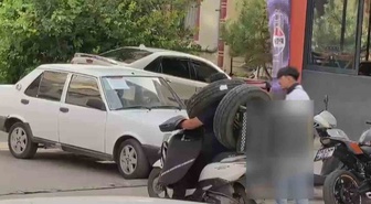 Ankara'da görenleri şaşkına çeviren kurye! Otomobil lastiğini boynuna asıp motosiklet kullandı