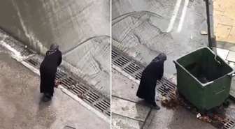 Belediye ekiplerini beklemeyen yaşlı kadın mazgalları bastonuyla temizledi