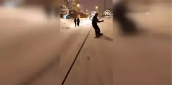 Van'ın karlı sokaklarında snowboard yaptı