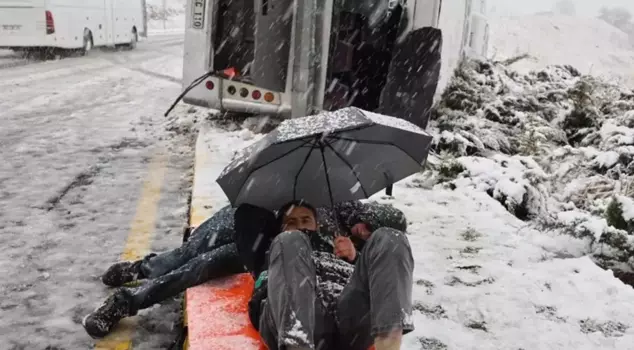 The worker's shuttle flipped over, waiting for the ambulance with an umbrella.