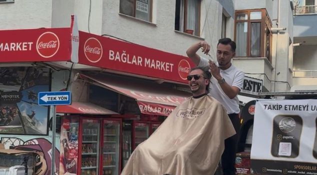 A barber pushing boundaries: A haircut in the back of a pickup truck, and while moving.