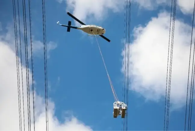 Helikoptere bağlı sepetle elektrik iletim hatlarına bakım yaparken ölüme meydan okuyorlar