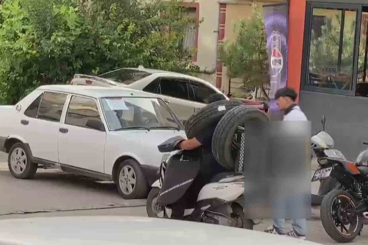 Ankara'da görenleri şaşkına çeviren kurye! Otomobil lastiğini boynuna asıp motosiklet kullandı