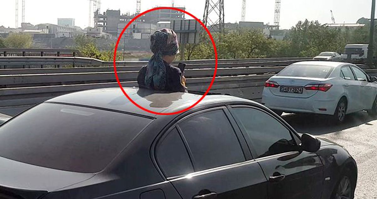 Aracın sunroof'undan çıkan kadın telefonla oynadı