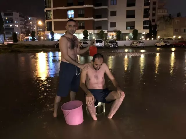 İzmir'de su kesintisine dikkati çekmek için yağmur suyuyla sokakta yıkandılar İzmir'de su kesintisine dikkati çekmek için yağmur suyuyla sokakta yıkandılar