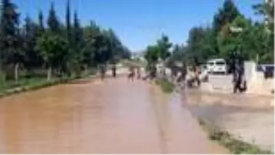 Çocukların patlayan borudan akan suda çamurla oyunu