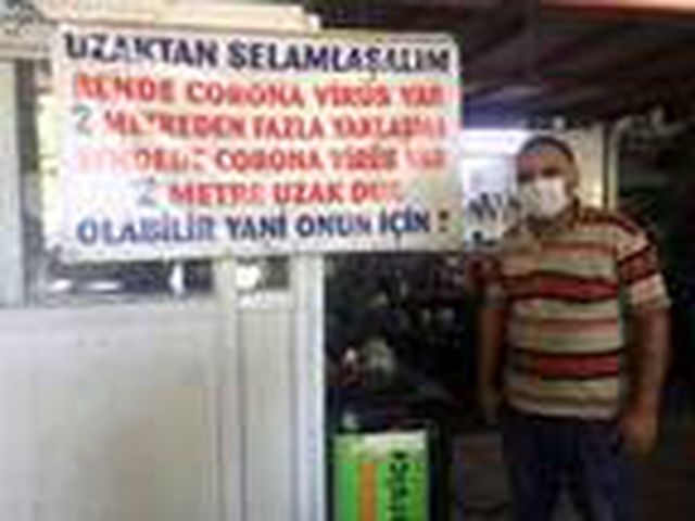 Sosyal mesafeye dikkat çekmek için iş yerine 'Bende koronavirüs var' yazılı pankart astı