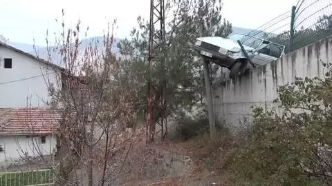 Telefon direğine çarpan otomobil 5 metre yüksekliğindeki istinat duvarının kenarında kaldı Telefon direğine çarpan otomobil 5 metre yüksekliğindeki istinat duvarının kenarında kaldı