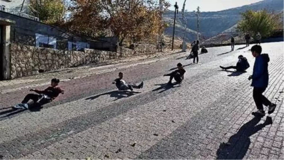 Henüz karın yağmadığı Gercüş'te çocuklar, yokuş aşağı tahta parçalarıyla kayıyor