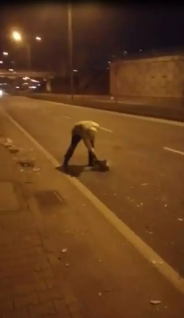 Elindeki kartonla yoldaki atıkları süpüren polise övgü Elindeki kartonla yoldaki atıkları süpüren polise övgü