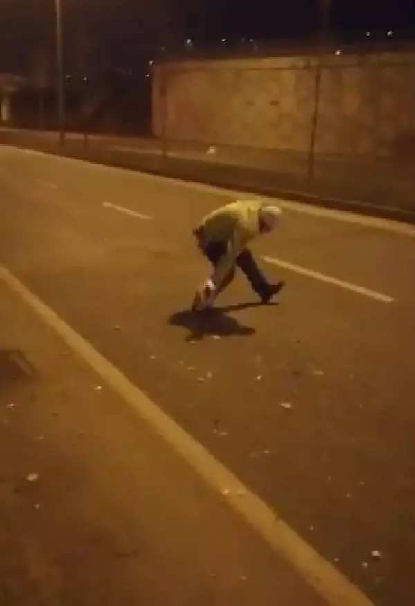 Elindeki kartonla yoldaki atıkları süpüren polise övgü Elindeki kartonla yoldaki atıkları süpüren polise övgü