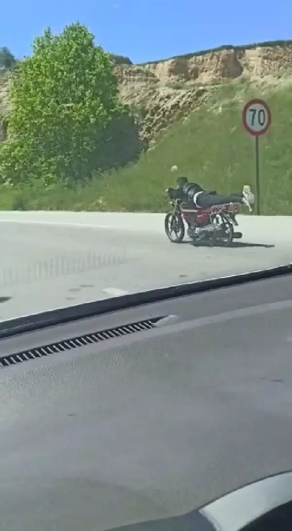 Üzerine uzandığı motosikletle tehlikeli yolculuk