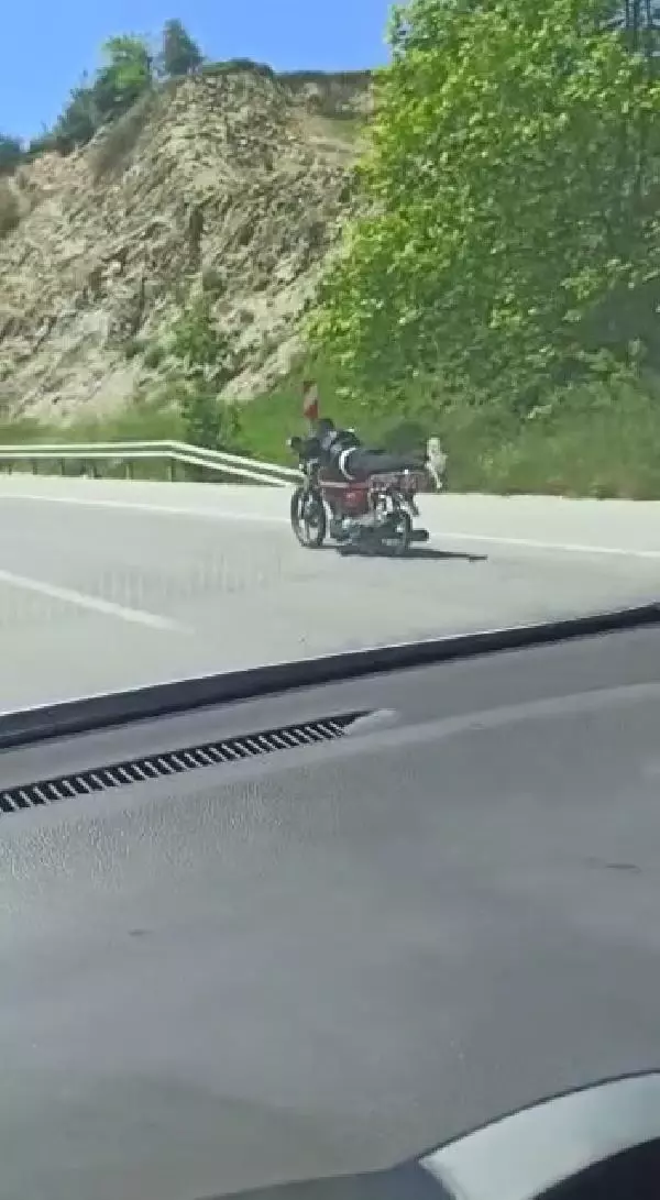Üzerine uzandığı motosikletle tehlikeli yolculuk