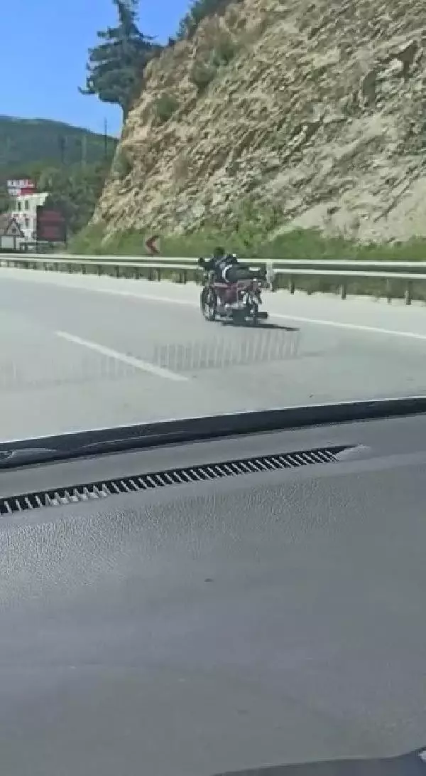 Üzerine uzandığı motosikletle tehlikeli yolculuk
