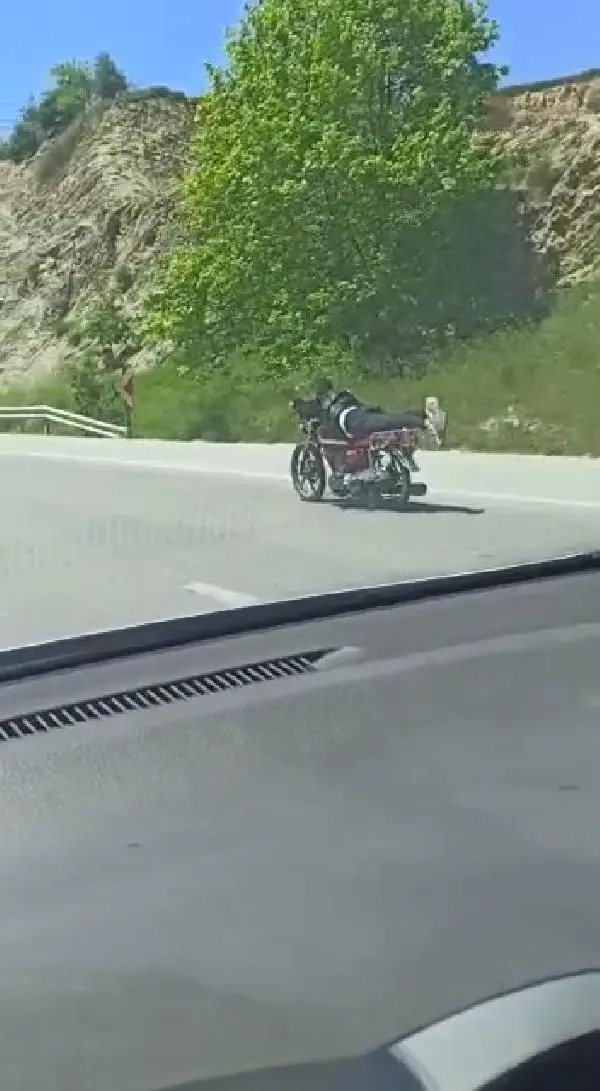 Üzerine uzandığı motosikletle tehlikeli yolculuk