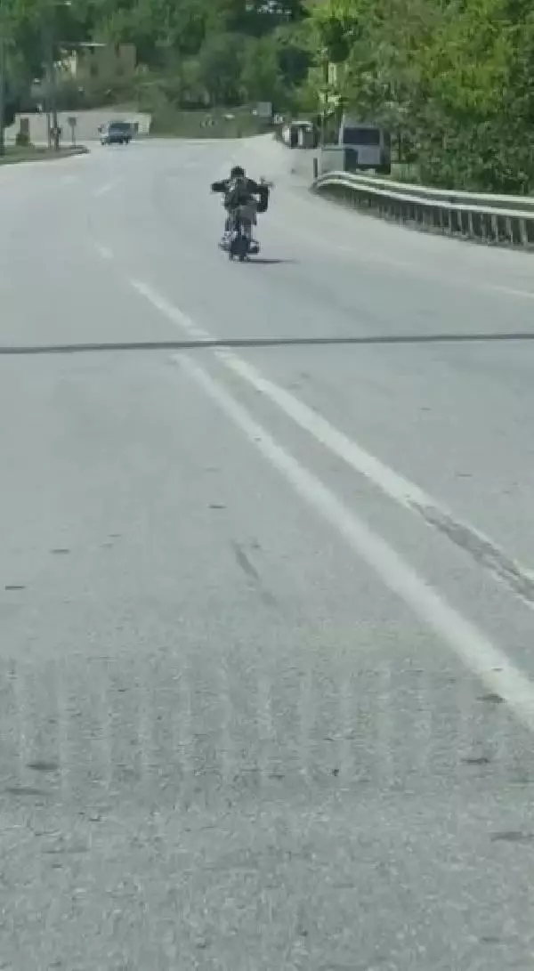 Üzerine uzandığı motosikletle tehlikeli yolculuk