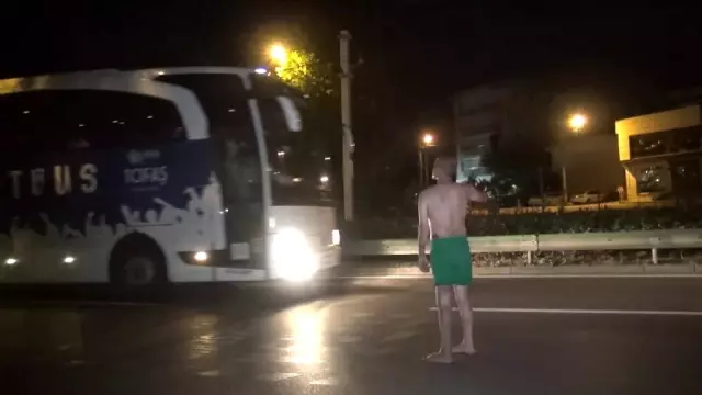 Araçlara aldırış etmeden yolda yarı çıplak yürüdü