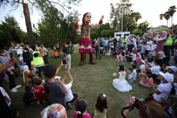 Little Amal walked along while refugee children sang songs