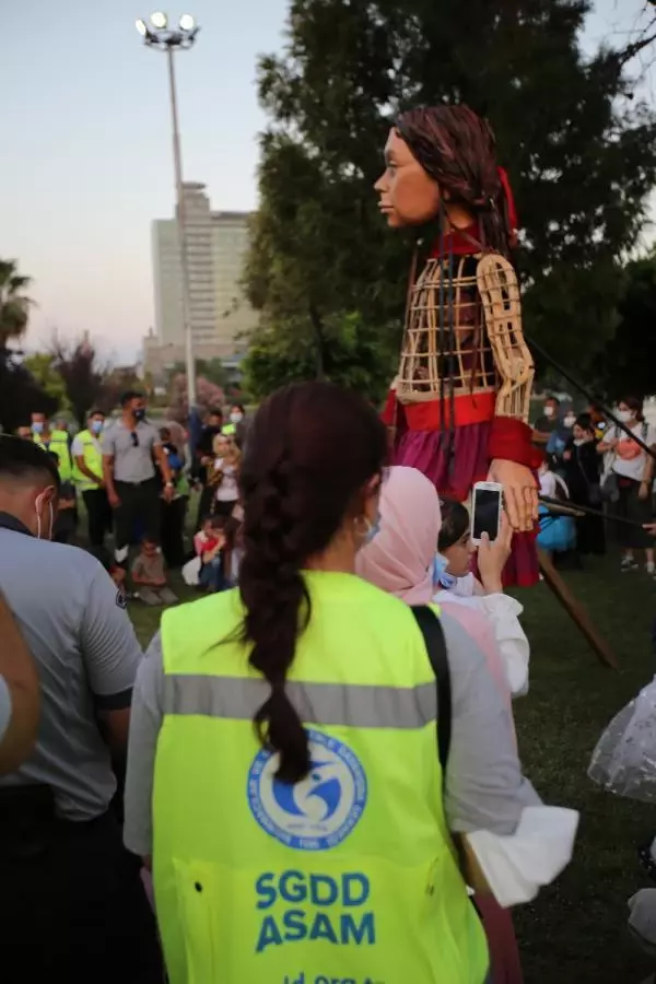 Little Amal walked along while refugee children sang songs