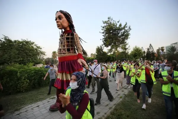 Little Amal walked along while refugee children sang songs