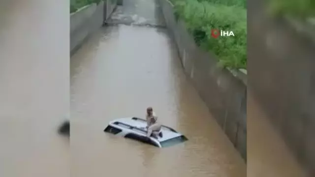 Hindistan'da selde mahsur kalan sürücü aracının üzerinde kurtarılmayı bekledi