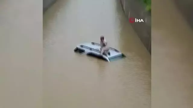 Hindistan'da selde mahsur kalan sürücü aracının üzerinde kurtarılmayı bekledi