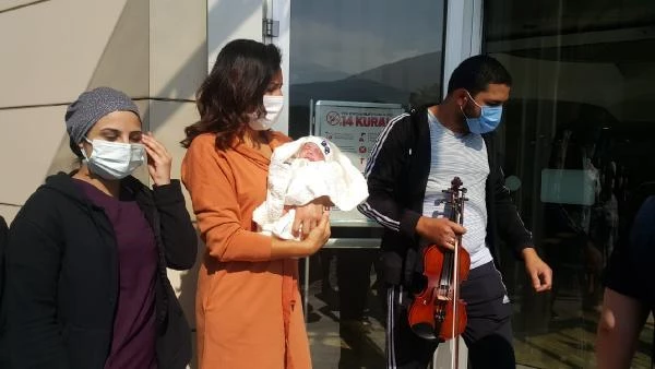 Taburcu olan bebeğini hastane kapısında kemanla karşıladı