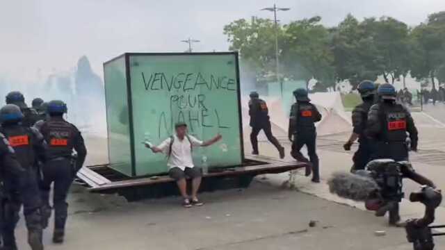 Fransa'da polis ve protestocuların çatısması arasında kalan bir kişi, hiçbir şey olmamış gibi sandviç yedi