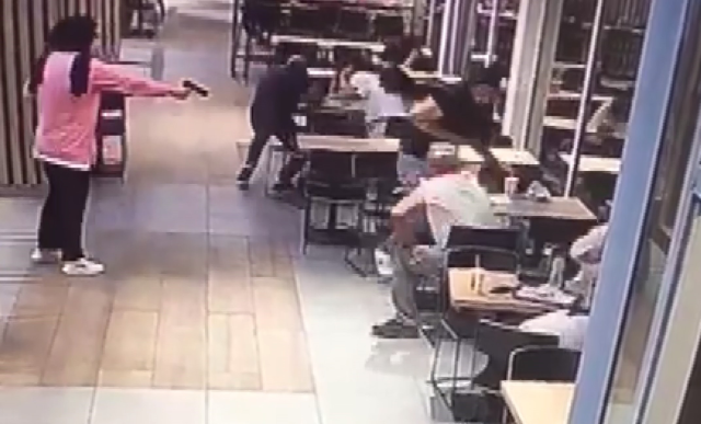 A woman calmly enters the cafe and shoots the man sitting at the table