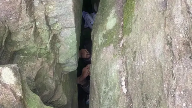 The woman trying to pick up her fallen phone got stuck upside down between the rocks.