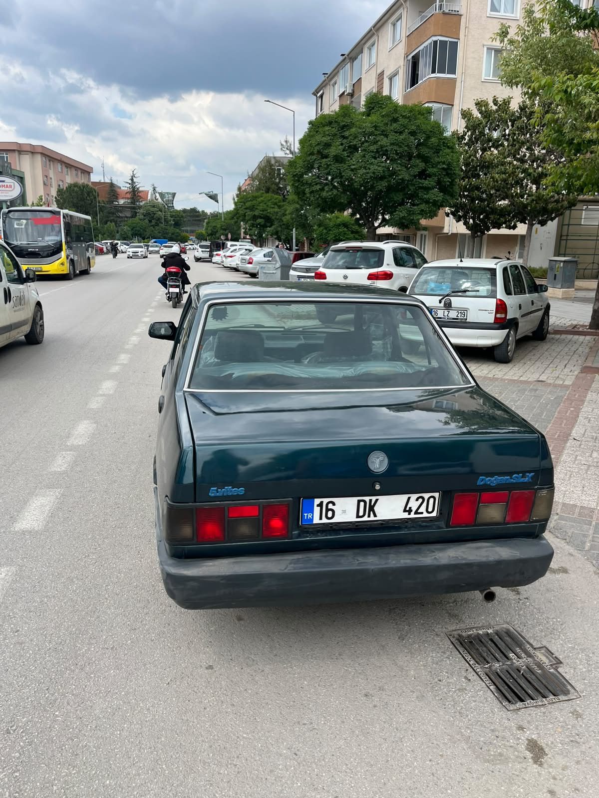 Otomobilinin sol ön kapısını açıp, ayağıyla tutarak trafikte ilerledi