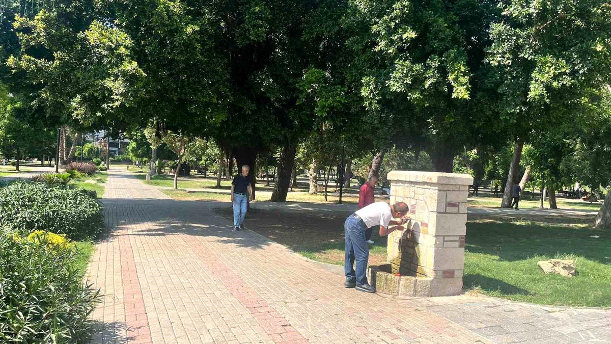 Adana'da parkta gölgelik bir alanda oturan insanlar