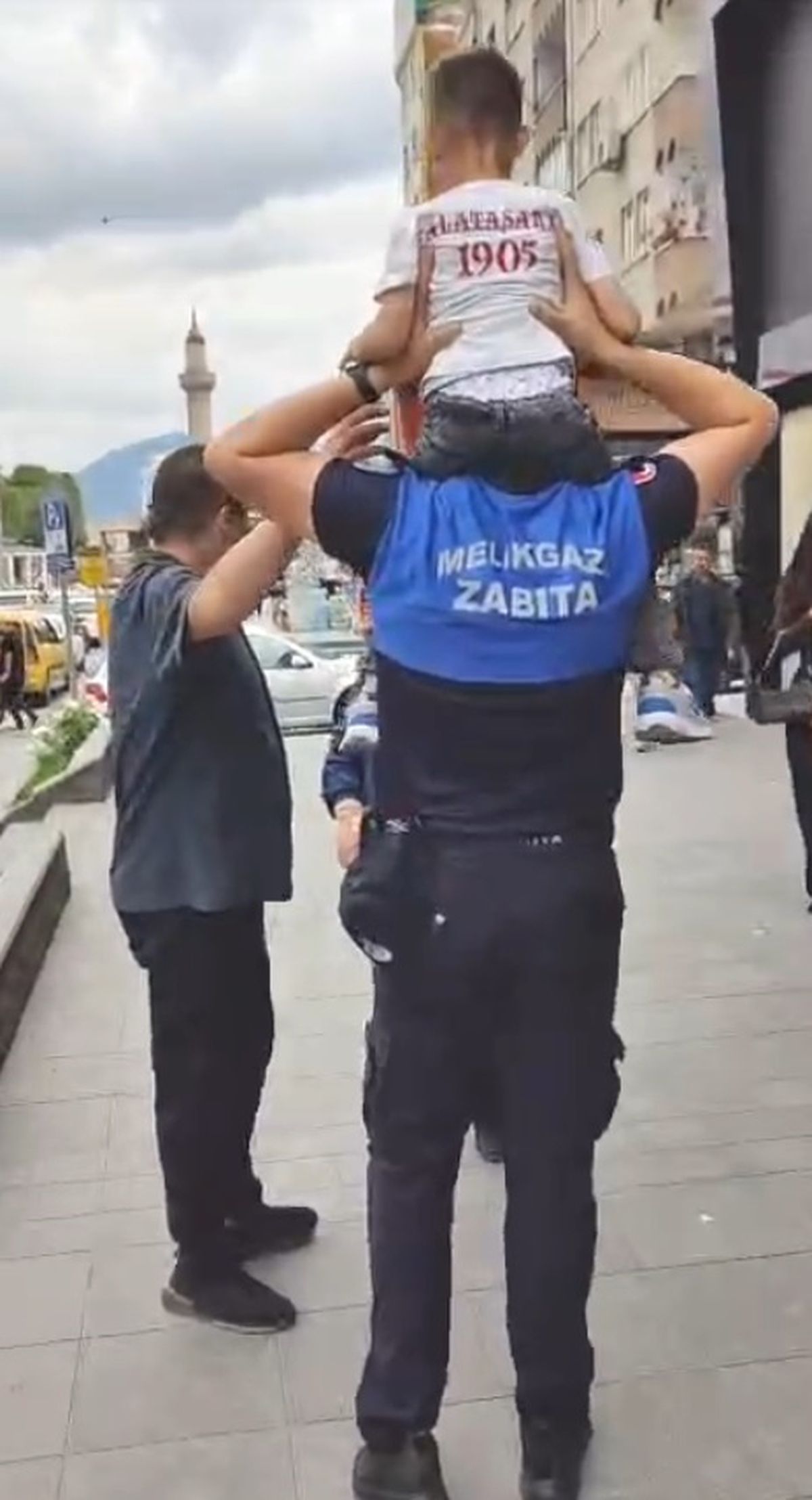 Zabıta memuru, omzunda taşıdığı küçük çocuğu babasına teslim ediyor.