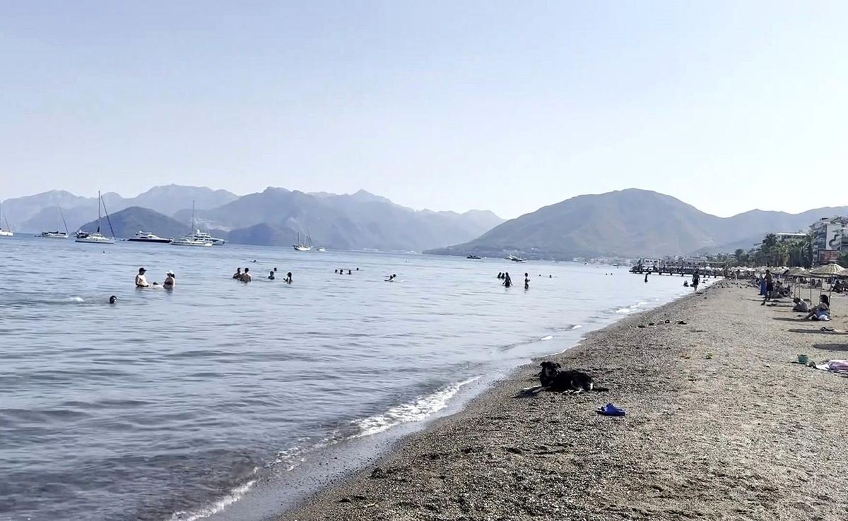 Marmaris'te güneşli bir günde kalabalık bir sahil manzarası.