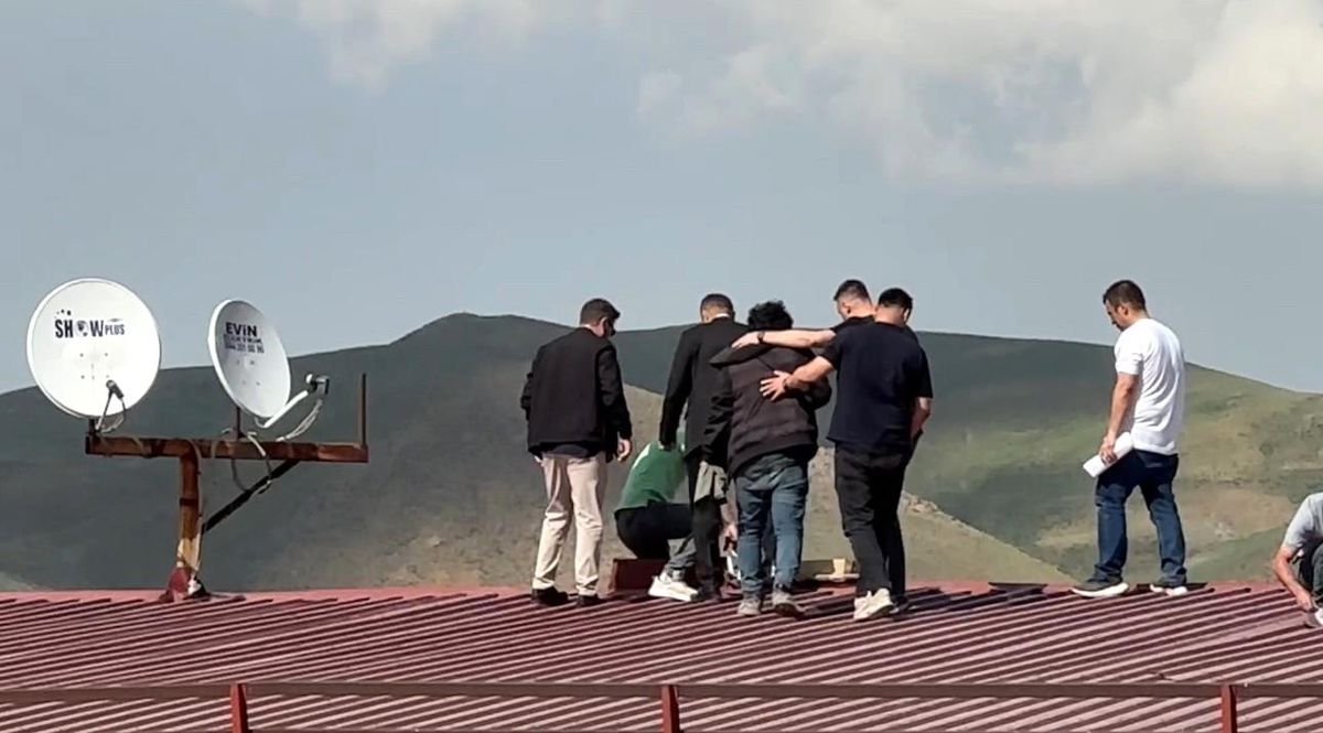 Hakkari'nin Yüksekova ilçesinde bir binanın çatısında intihar girişiminde bulunan şahsın polis ve itfaiye ekiplerince ikna edilerek indirildiği an.
