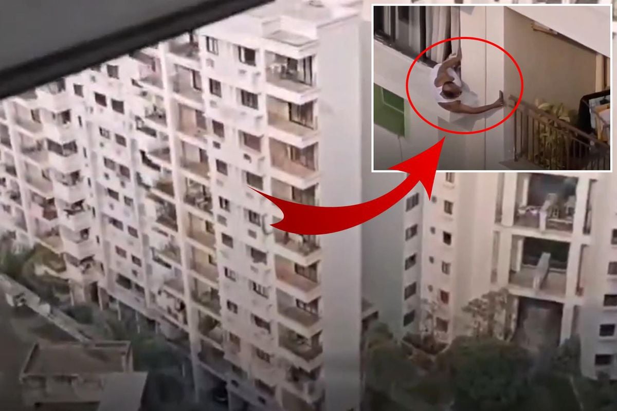 Hindistan'da bir apartman sakini, kendi dairesinin penceresinden dışarı sarkarak yan komşusunun dairesini gözetlerken çekilmiş görüntü.
