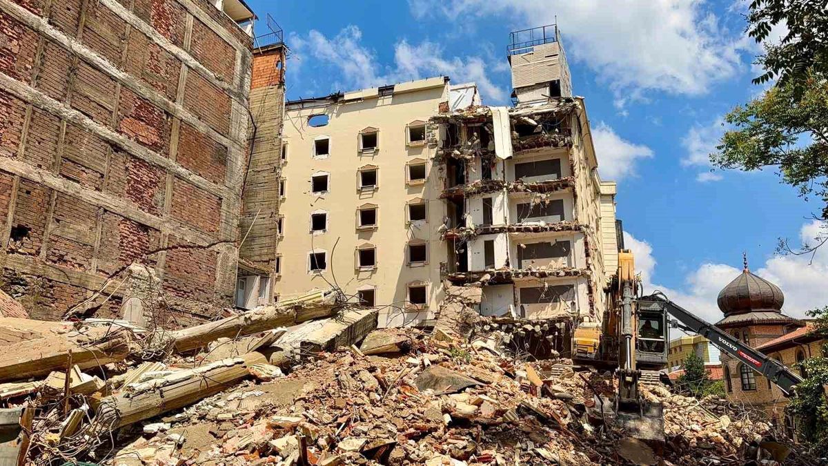 Afyonkarahisar'da eski bir otelin yıkımı sırasında çöken molozların bitişikteki iş hanına zarar verdiği anı gösteren görsel.
