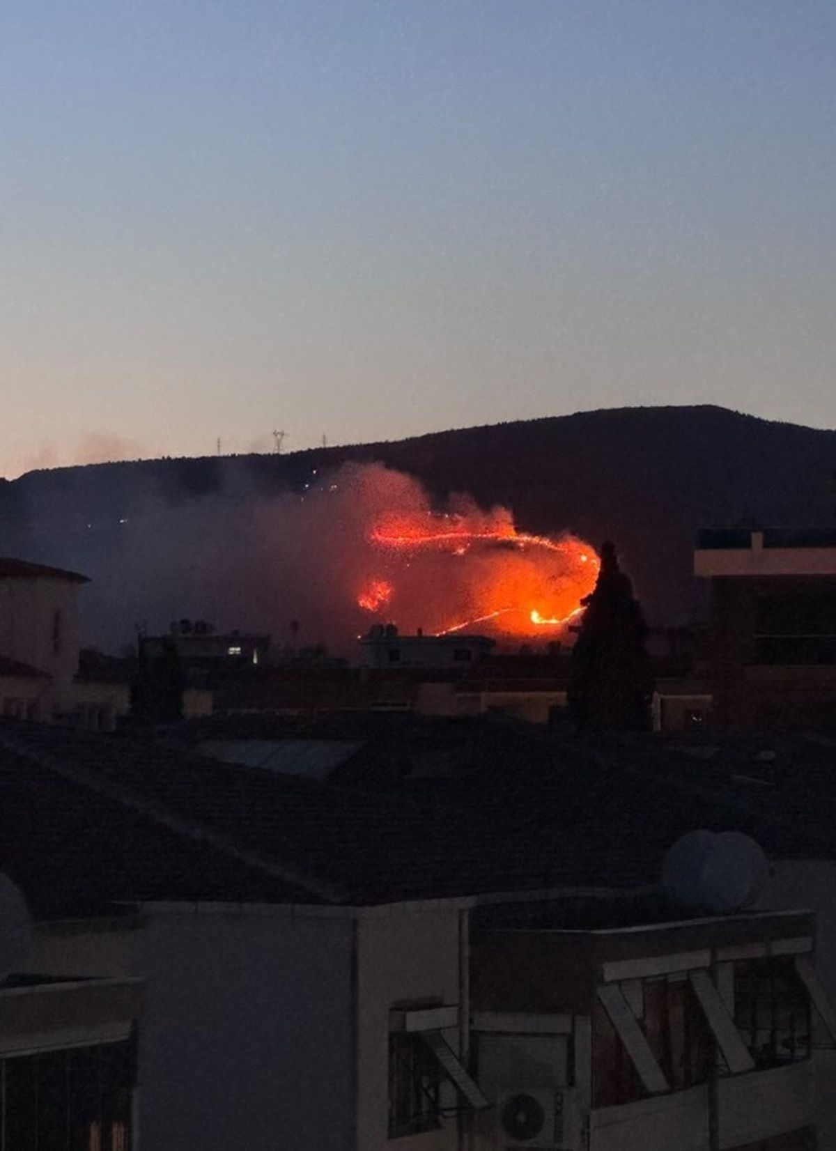 İzmir Çiğli'de otluk alanda çıkan yangına ekiplerin müdahalesini gösteren görsel.