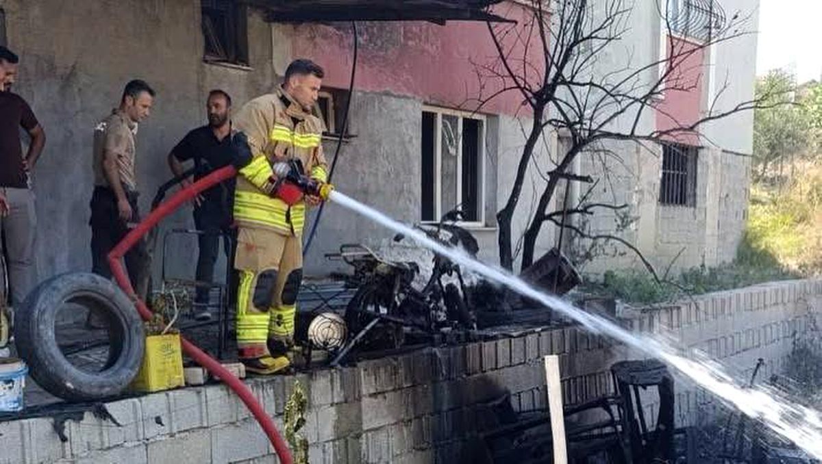 Hatay'ın Antakya ilçesinde bir evinin önünde bulunan motosiklet ve eşyaların alev aldığı an.